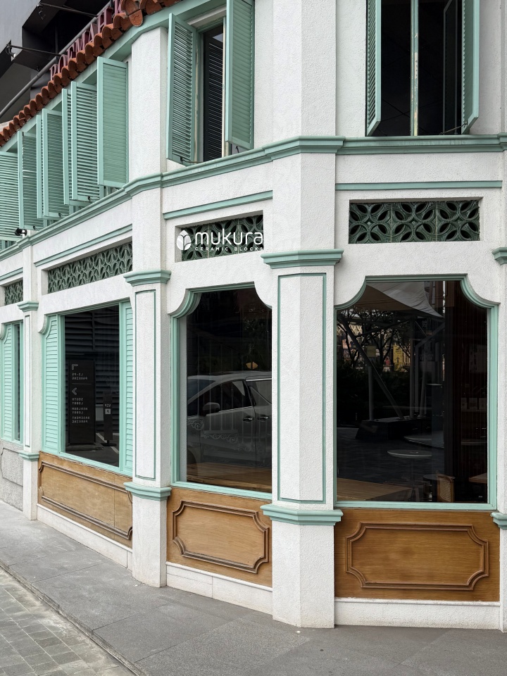 Fasad kolonial Roemah Koffie berhias aksen hijau pada moulding dan jendela kayu serta roster keramik granit Rosentro